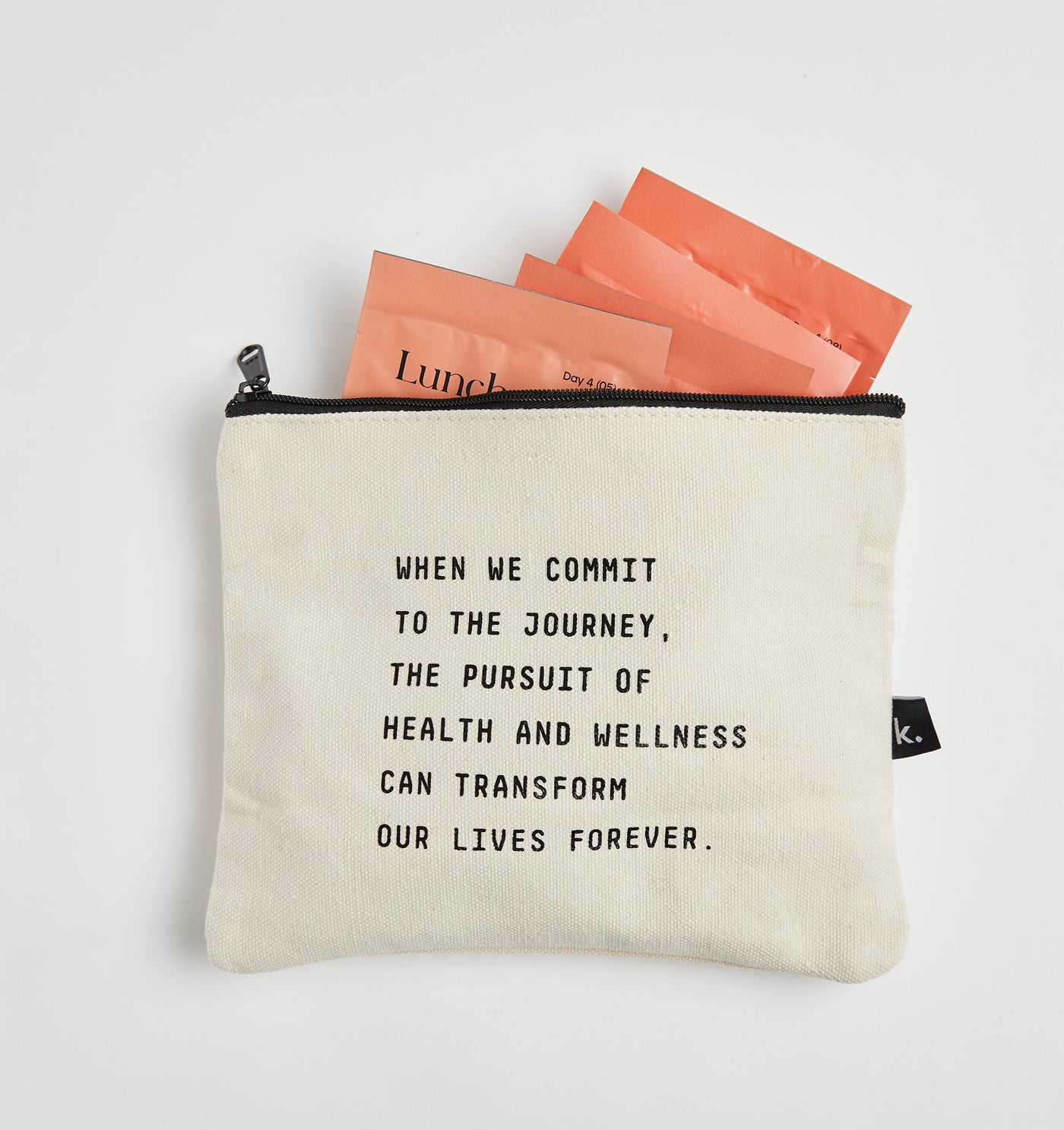 A beige pouch with a motivational quote, accompanied by Kroma’s on-the-go sachets, set against a light background.
