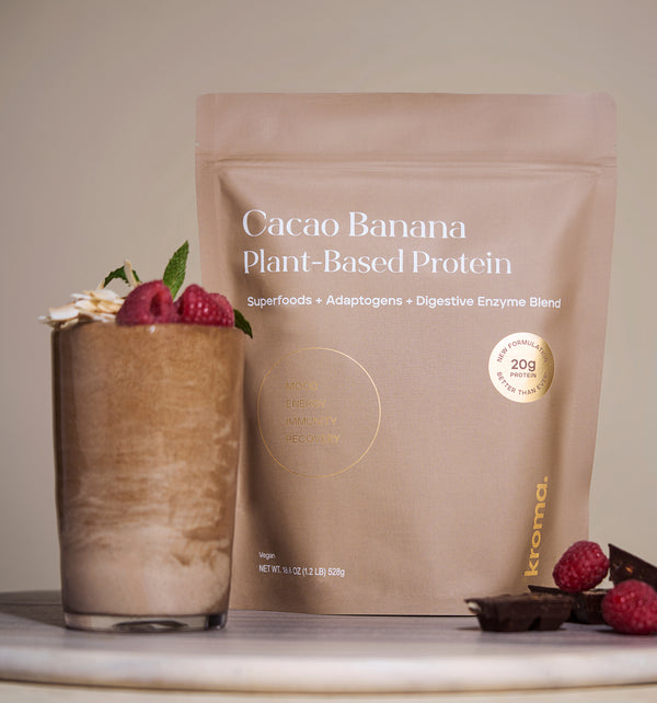 Pic of Cacao Banana plant-based protein package with a glass of protein shake on a neutral background.